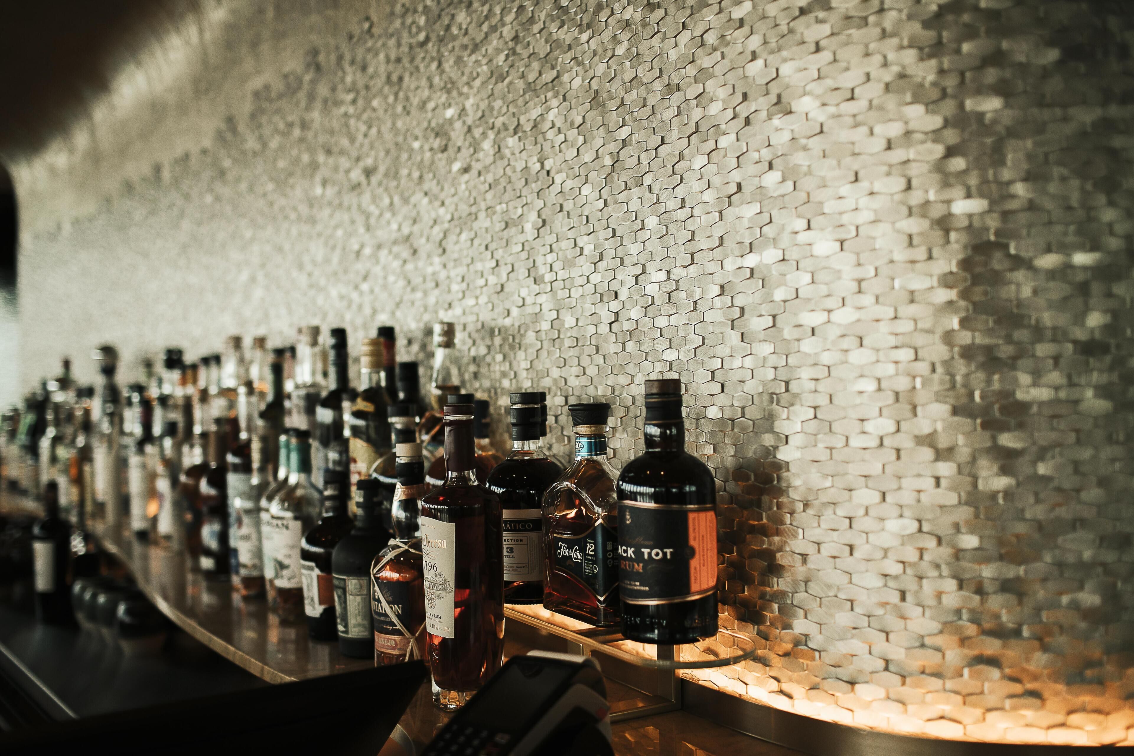 A bar with a hexagonal patterned wall and various bottles of liquor.
