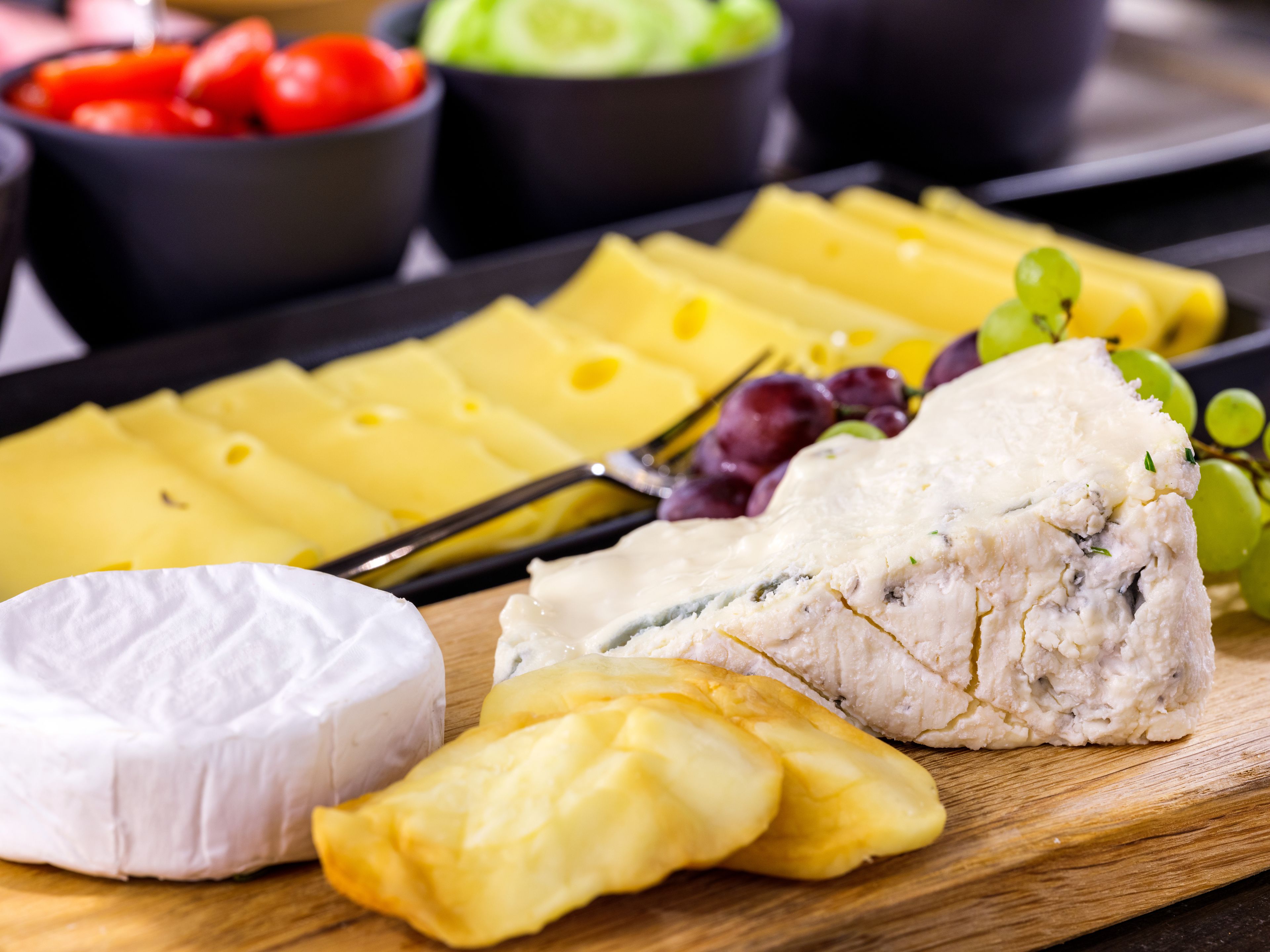 A charcuterie board with various cheeses, grapes, and olives.