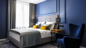 A modern bedroom with a bed, bedside tables, a chair, and a window with curtains.