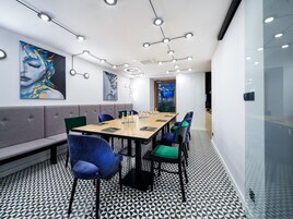 A modern meeting room with a long table, comfortable seating, and artwork on the walls.