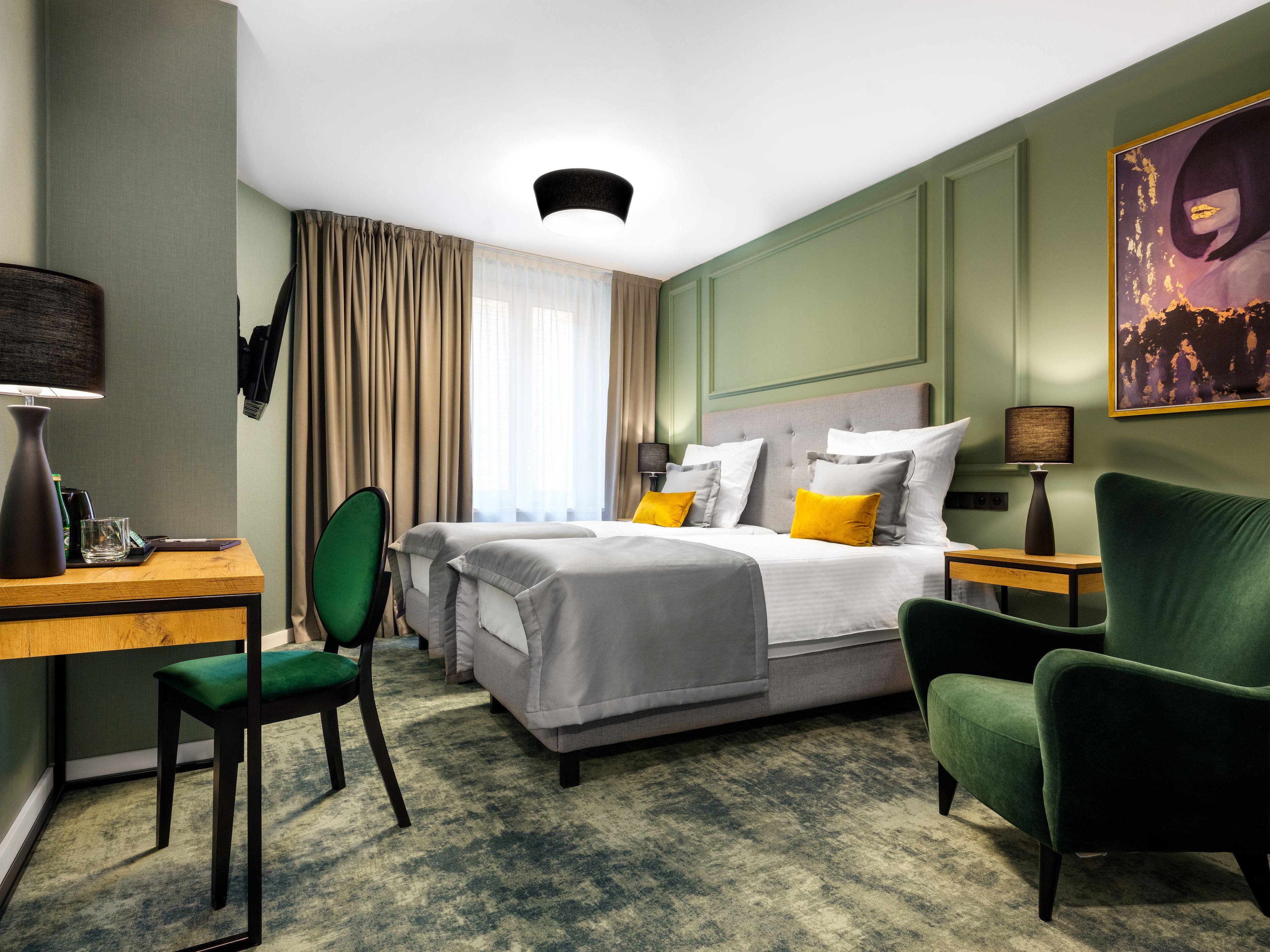 Habitación de hotel con dos camas, un escritorio, una silla y un cuadro en la pared.