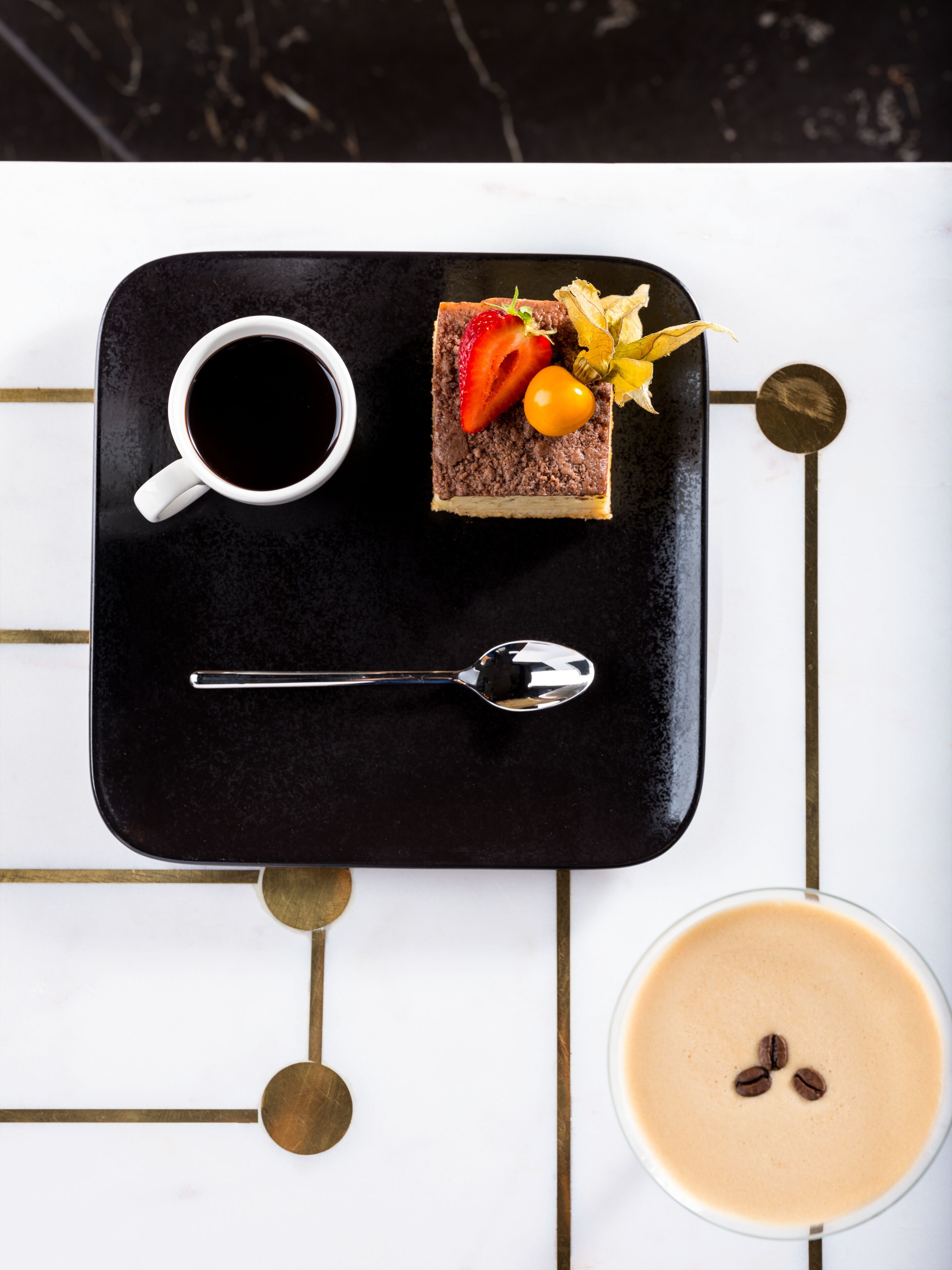 Una bandeja con una porción de pastel, una taza de café y una cuchara.