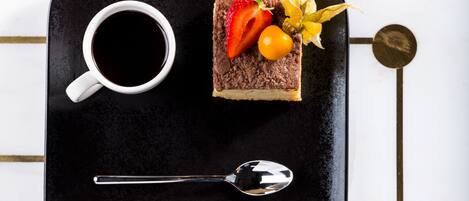 Una bandeja con una porción de pastel, una taza de café y una cuchara.