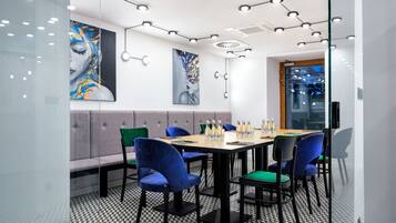 A modern meeting room with a glass partition, a round table, and blue chairs.