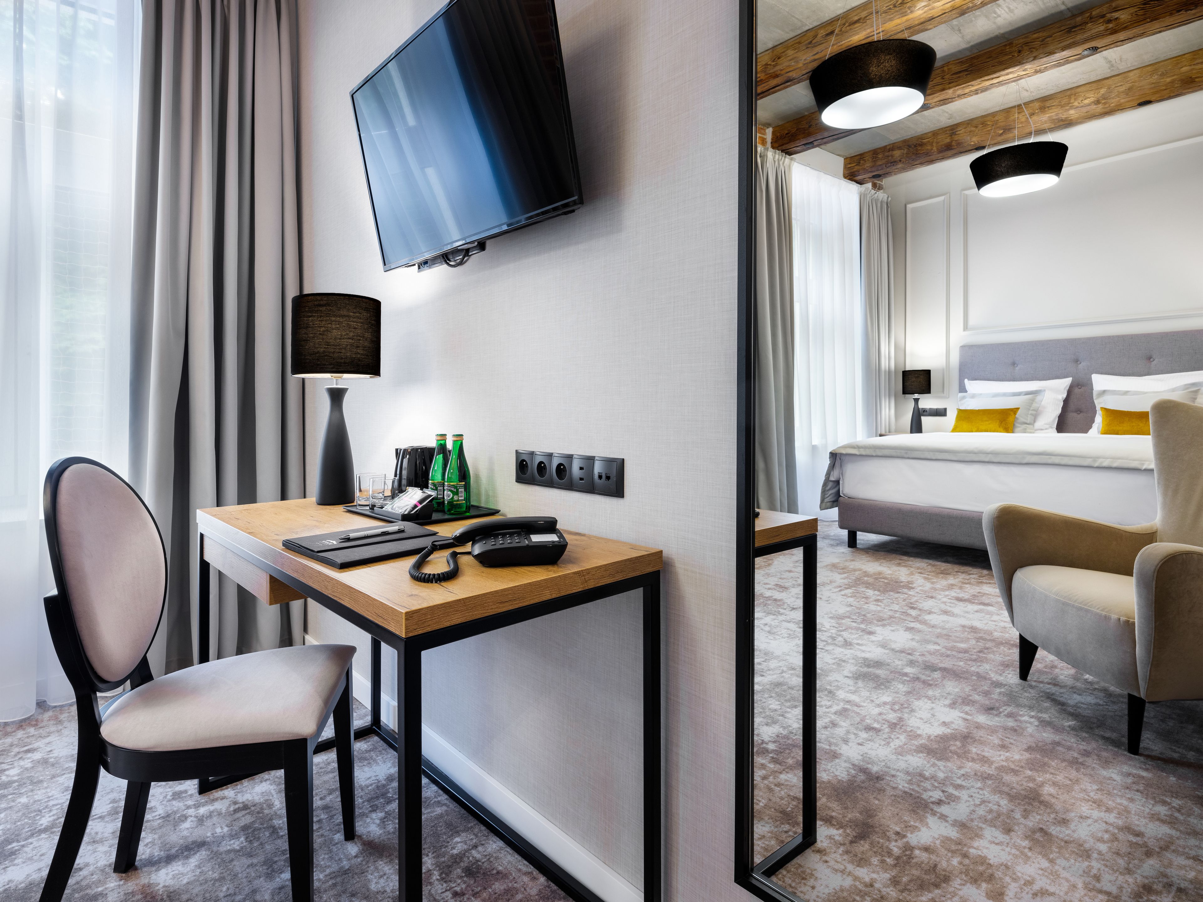 Habitación de hotel con escritorio, silla, cama y televisor montado en la pared.