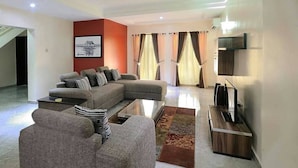 A modern living room with a sectional sofa, a flat-screen TV, and a coffee table. - Aden 360 Apartments By Intra (Lagos)