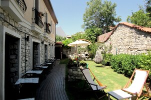 Un patio al aire libre con mesas y sillas, una pared de piedra y una terraza de madera.