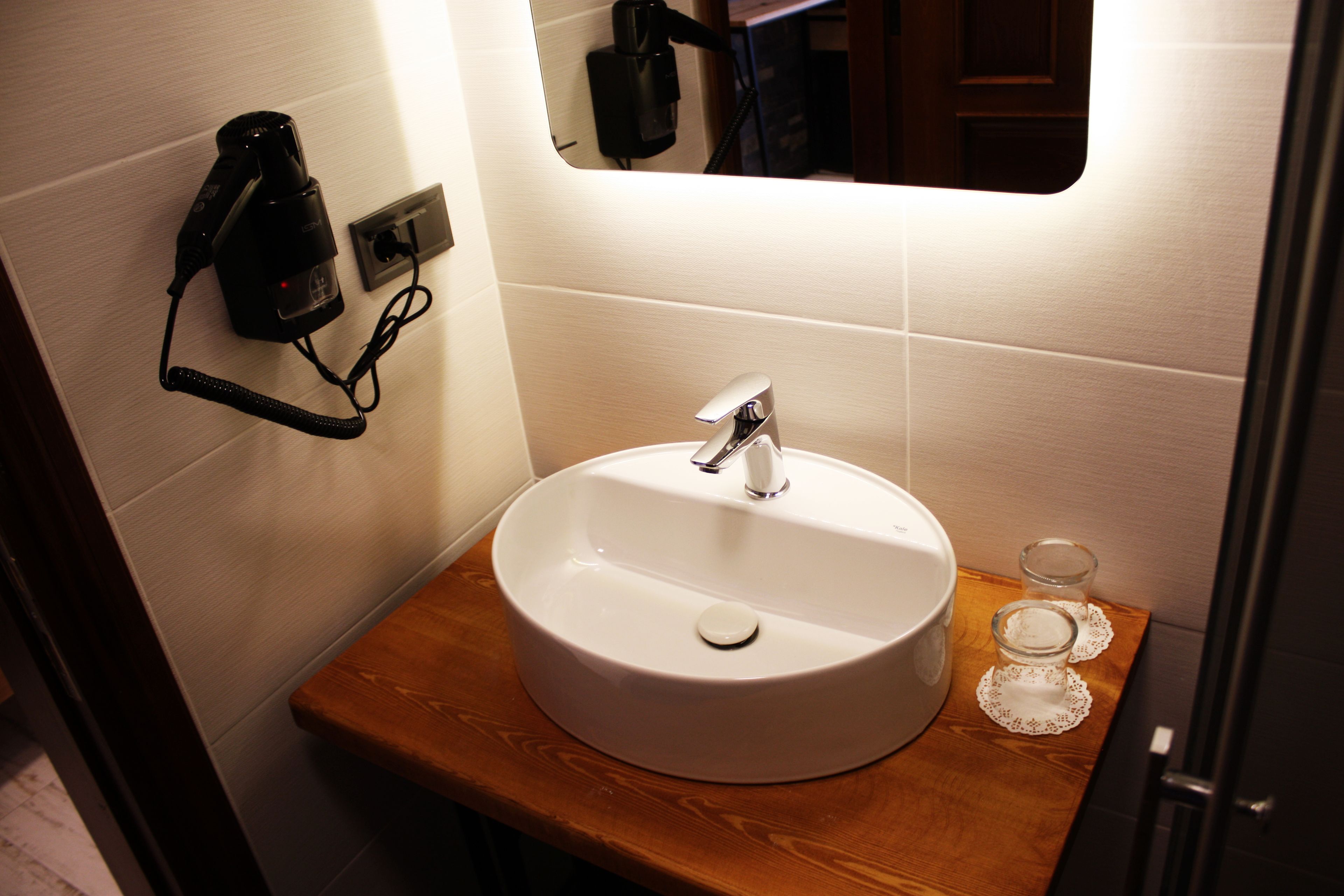 A bathroom with a white sink, a wooden countertop, and a mirror.