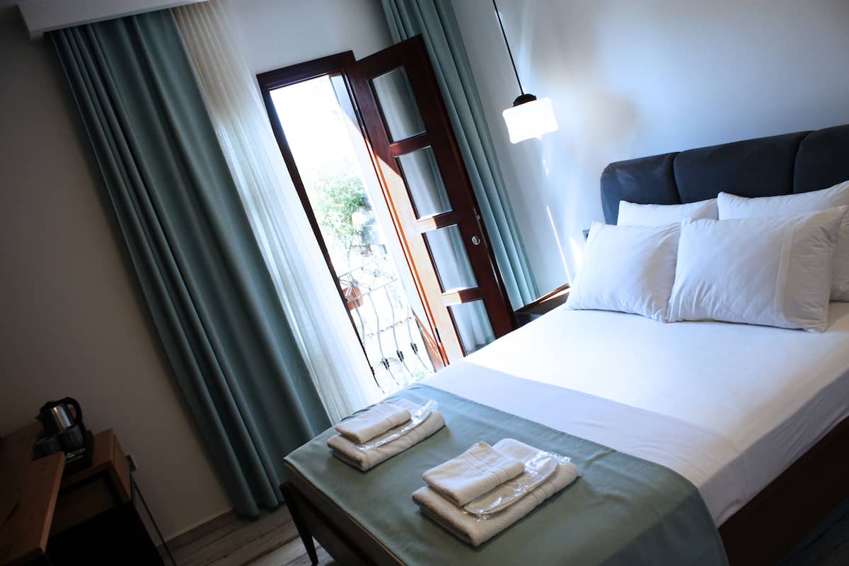A hotel room with a bed, a nightstand, and a window with curtains.