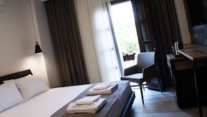 A hotel room with a bed, a desk, a chair, and a view of greenery outside. - Pintura Urla Butik Otel & Sanat Galerisi (Urla)