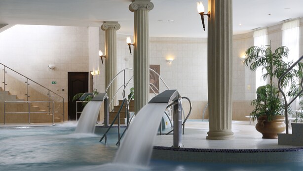 A hotel lobby with a central water feature, columns, and a staircase. - Hotel Bristol (Karlovy Vary)