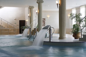 Eine Hotelhalle mit einem zentralen Wasserspiel, Säulen und einer Treppe.