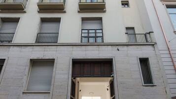 Un immeuble à plusieurs étages doté d’une entrée centrale, de balcons à chaque étage et d’une enseigne indiquant qu’il s’agit d’un espace commercial ou de bureaux.