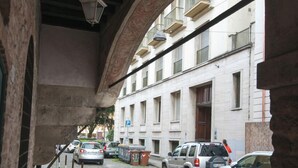 A cobblestone street with parked cars and a building with balconies. - Casa al Carmine (Padova)