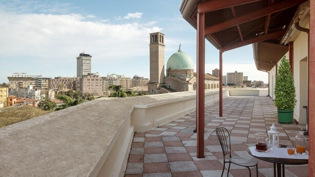 A rooftop terrace with a table set for two, overlooking a cityscape with historic buildings and a prominent dome structure. - Casa al Carmine (Padova)