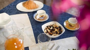 A breakfast table with croissants, a bowl of mixed nuts, and a glass of orange juice.