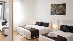 A hotel room with two beds, each with a white and brown bedspread, a nightstand with a lamp, and a painting on the wall. - Casa al Carmine (Padova)