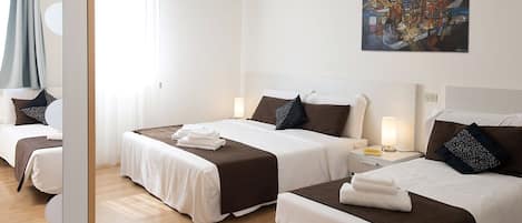 Ein Hotelzimmer mit zwei Betten, jeweils mit einer weißen und braunen Bettdecke, einem Nachttisch mit Lampe sowie einem Bild an der Wand.