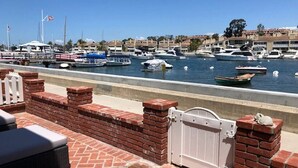Un port de plaisance avec des bateaux amarrés, un mur de briques avec une porte, et une vue dégagée sur l’eau.
