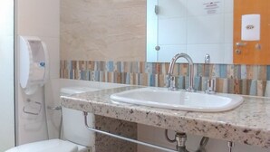 A bathroom with a white toilet, a sink with a mirror above, and a hand dryer. - Hotel Venturim (Venda Nova Do Imigrante)