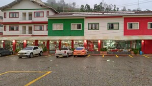 A row of colorful buildings with a parking lot in front. - Hotel Venturim (Venda Nova Do Imigrante)
