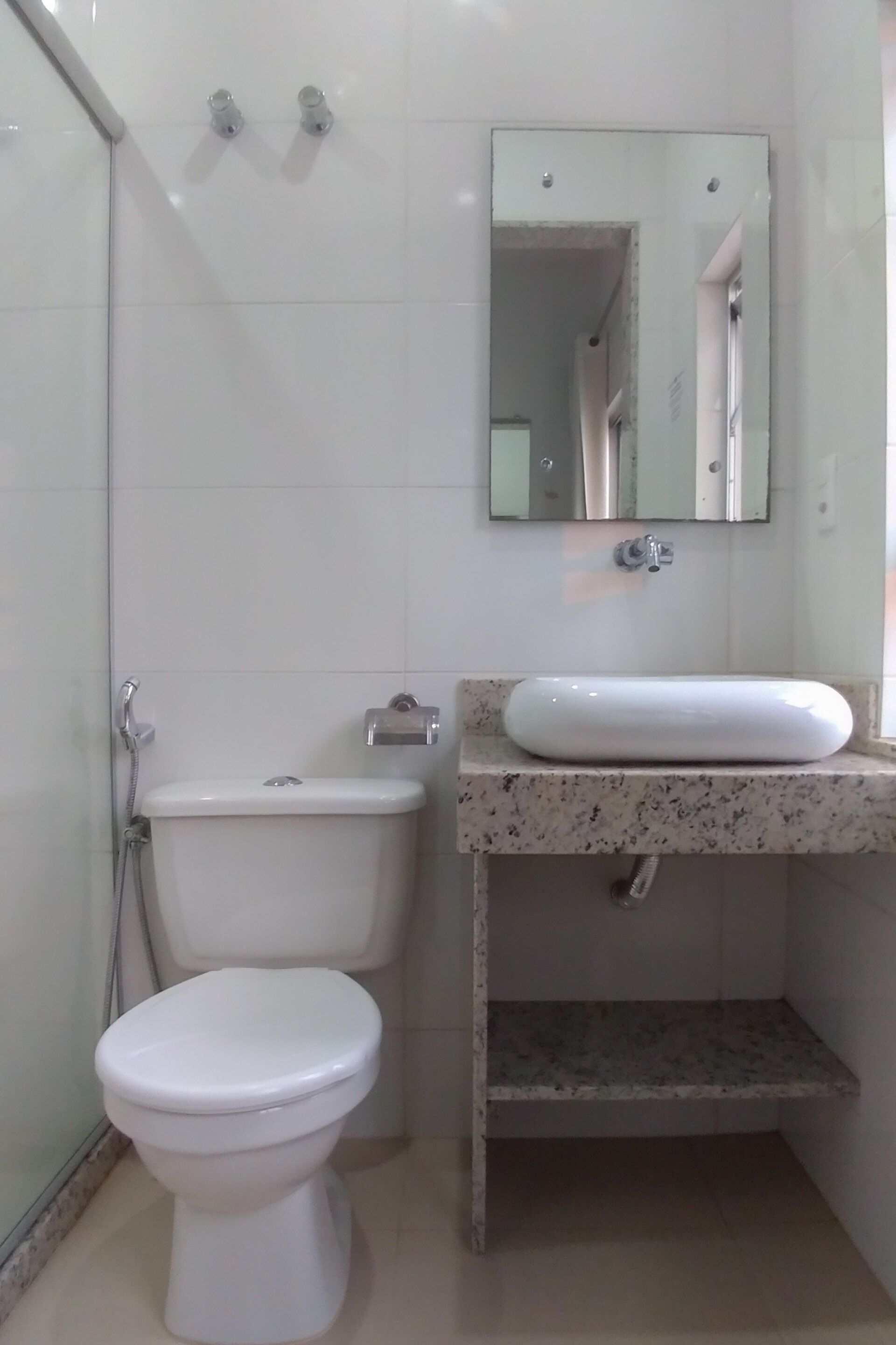 A bathroom with a toilet, a sink, and a mirror.