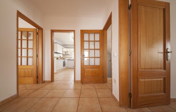 Un pasillo con puertas de madera que dan a una zona de cocina.
