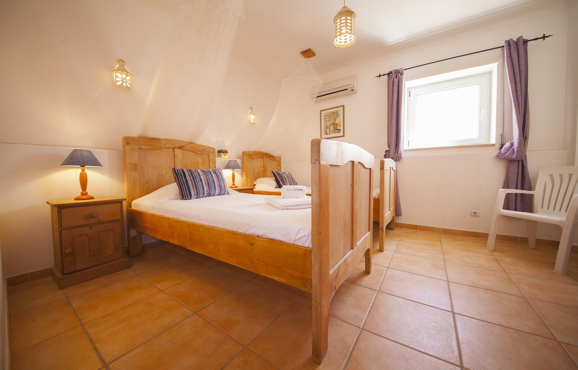 A bedroom with a wooden bed, a nightstand, a chair, and a window with curtains.