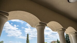 Vista attraverso una struttura architettonica ad arco con colonne, su un cielo sereno e un paesaggio lontano.