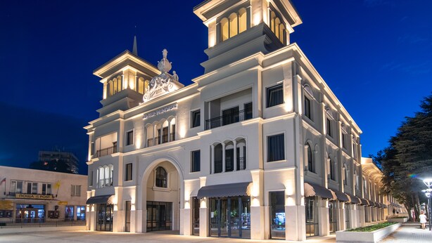 Un edificio storico con un ingresso ad arco centrale, numerosi balconi e una torre imponente.