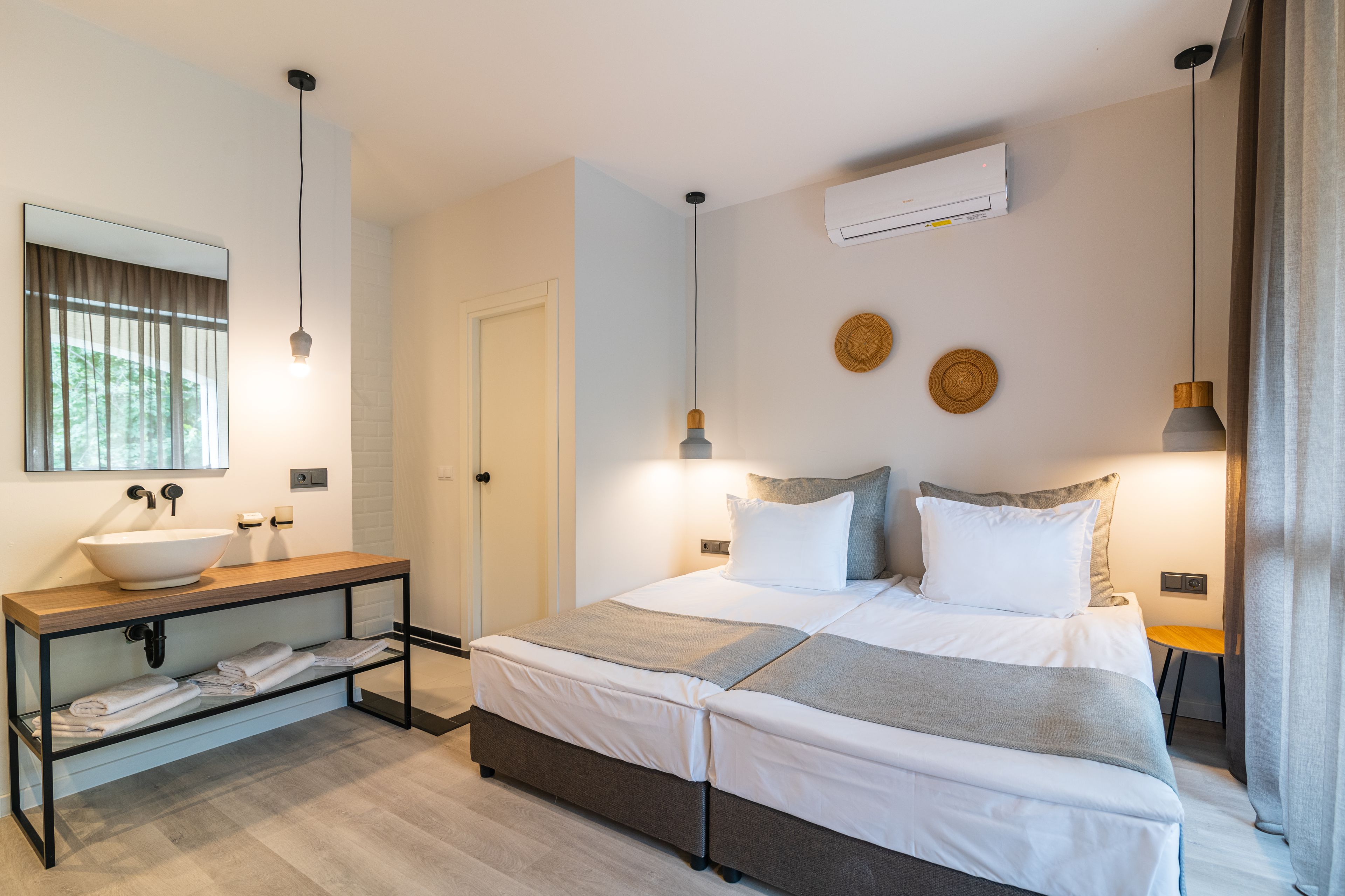 A modern bedroom with a large bed, bedside tables, a built-in sink, and a mirror.
