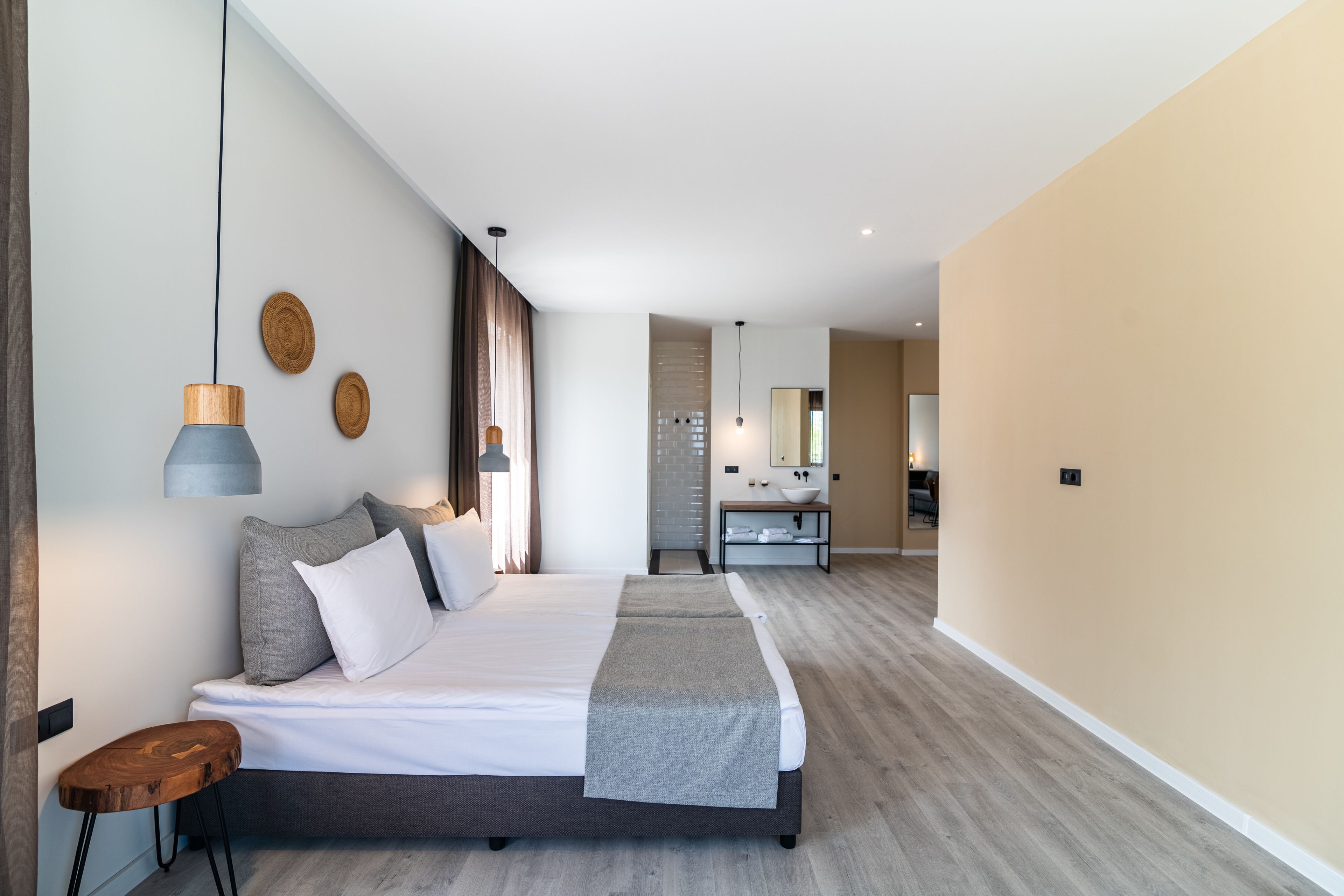 Ein modernes Hotelzimmer mit einem großen Bett, einem Nachttisch und einem im Hintergrund sichtbaren Badezimmer.