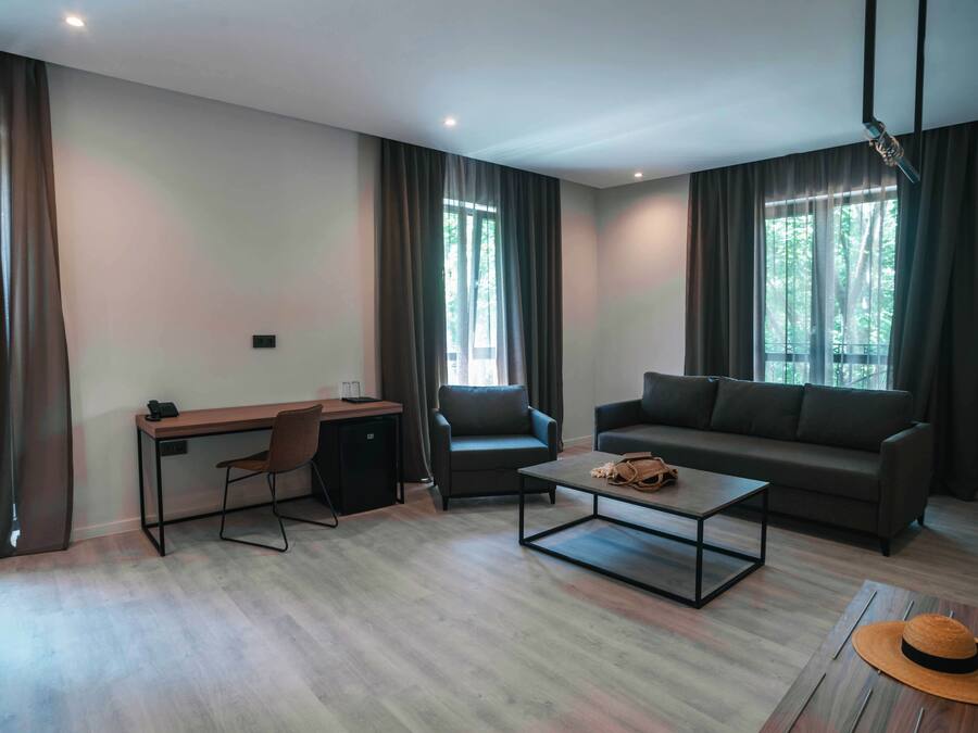 Una sala moderna con un escritorio, dos sillas, un sofá y una mesa de centro.
