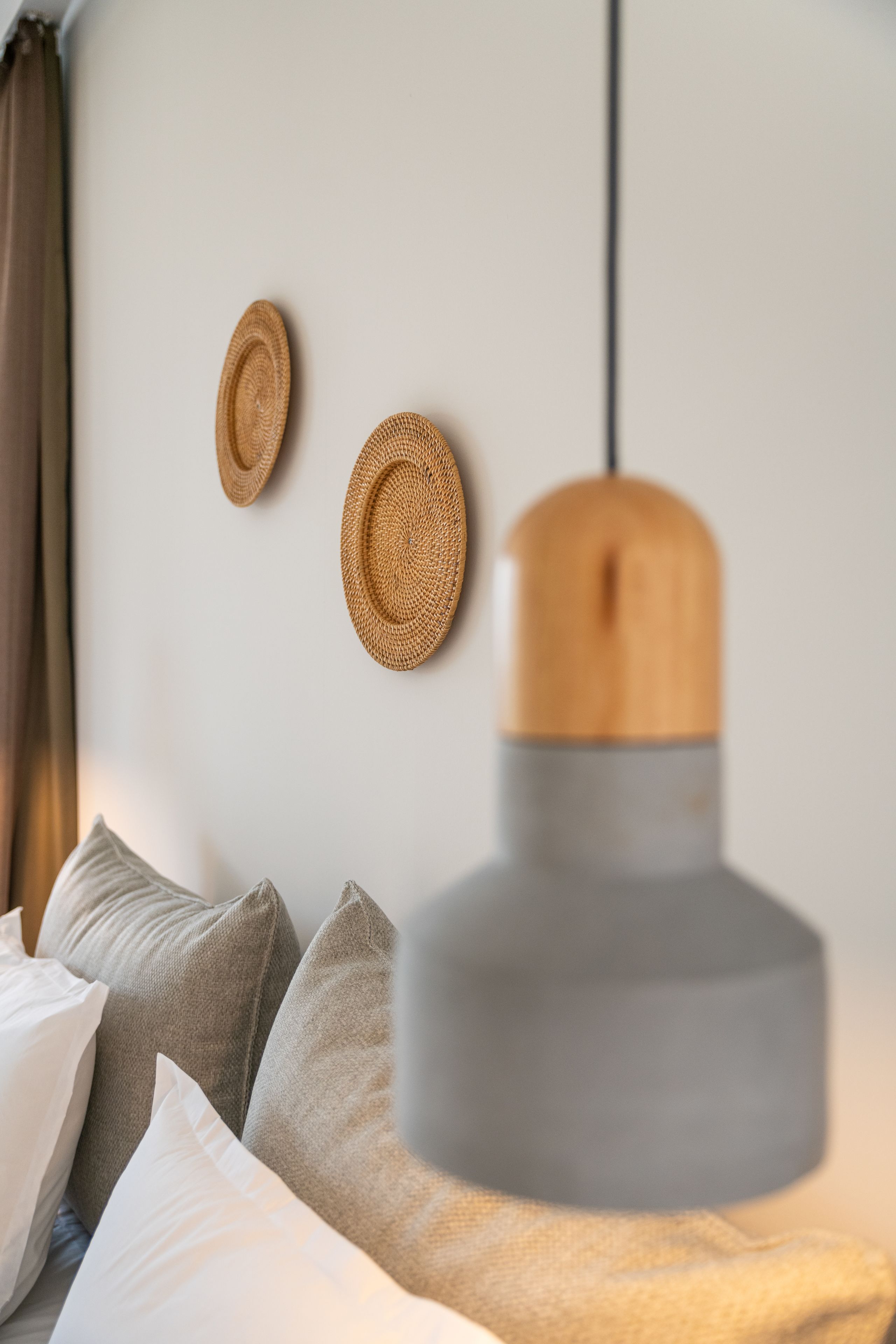 Una camera da letto moderna con un divano grigio, cuscini bianchi e una lampada a sospensione in legno.