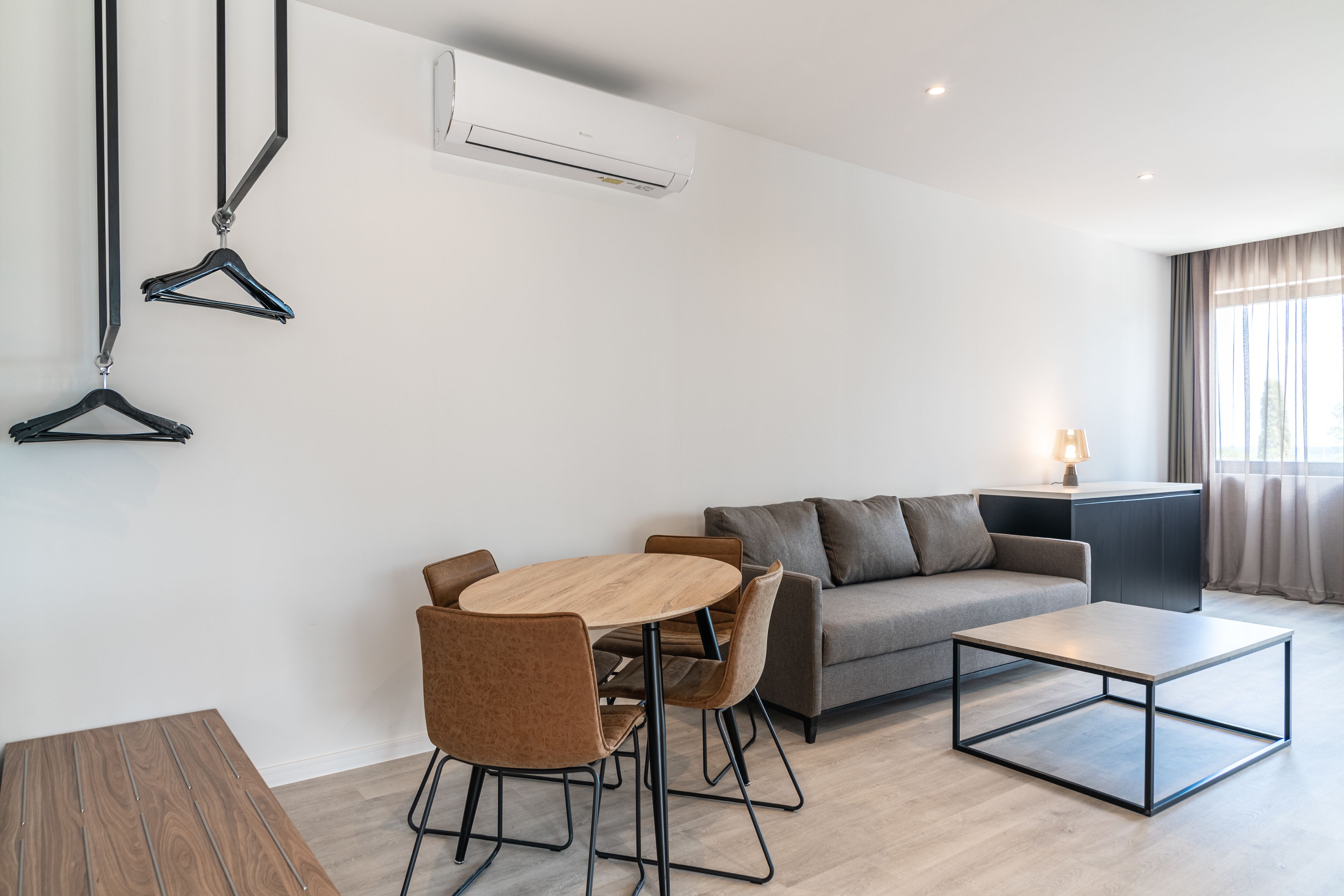 A modern living room with a sofa, a dining table, chairs, and a coffee table.