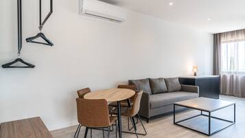 A modern living room with a sofa, a dining table, chairs, and a coffee table.