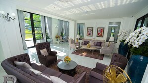 Uma sala de estar espaçosa com um amplo sofá, uma mesa de centro e um ventilador decorativo.