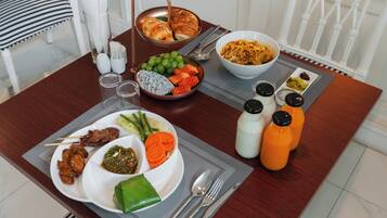 Ein Esstisch mit verschiedenen Speisen, darunter eine Nudelschüssel, ein Teller mit Fleisch und Gemüse sowie eine Platte mit Croissants.
