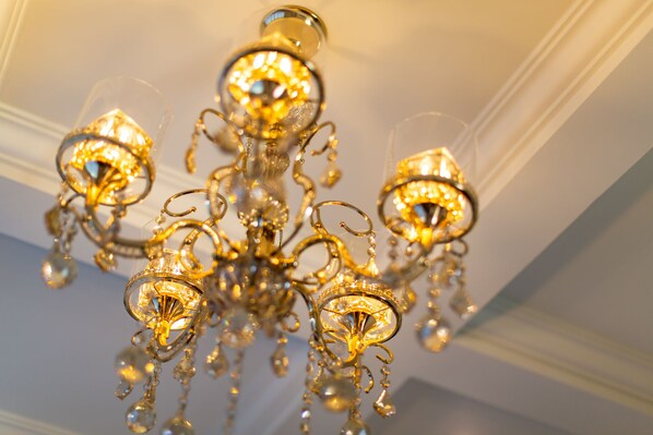 A chandelier with multiple arms and crystal decorations. - Merchant Villa (Chiang Mai)