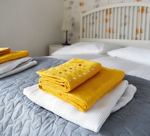 A neatly made bed with a grey quilt, a white pillow, and a folded yellow towel on top. - Boardinghouse Oldenburg (Oldenburg)