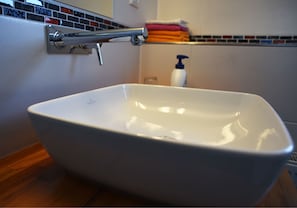 A white freestanding bathtub with a chrome faucet, a tiled backsplash, and a wooden floor. - Boardinghouse Oldenburg (Oldenburg)