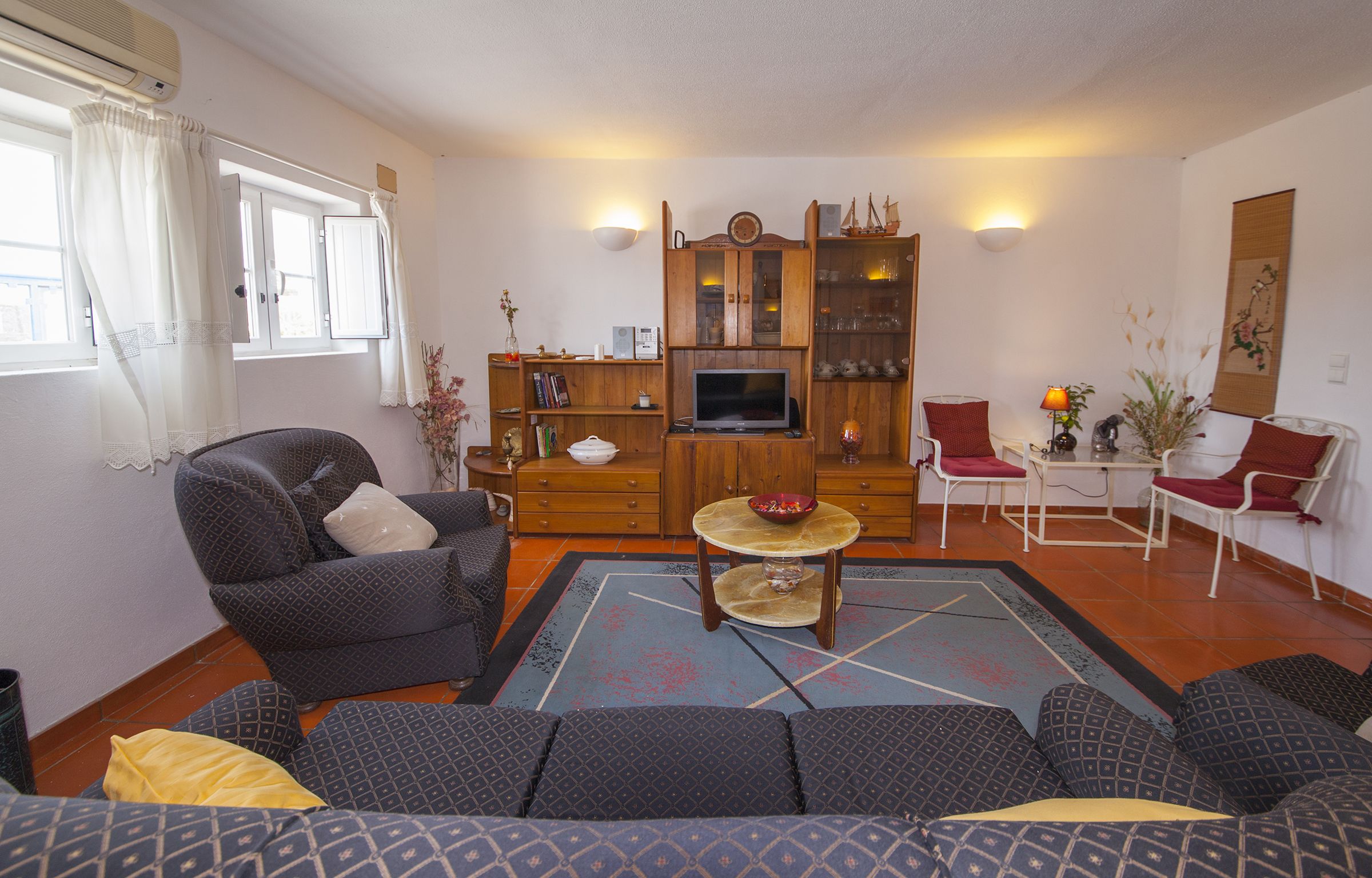 A living room with a sofa, chairs, a TV, and a wooden cabinet.