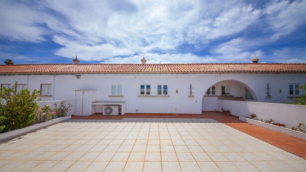 A building with a tiled roof, a courtyard with a tiled floor, and a white exterior. - D10 - Ferragudo Townhouse by DreamAlgarve (Lagoa)