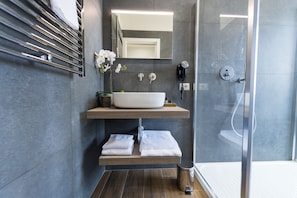 A modern bathroom with a large sink, a mirror, a towel rack, and a shower area. - Loft Rooms Trastevere (Rome)