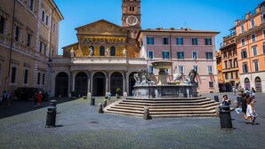 A historic square with a central fountain, a clock tower, and classical architecture. - Loft Rooms Trastevere (Rome)