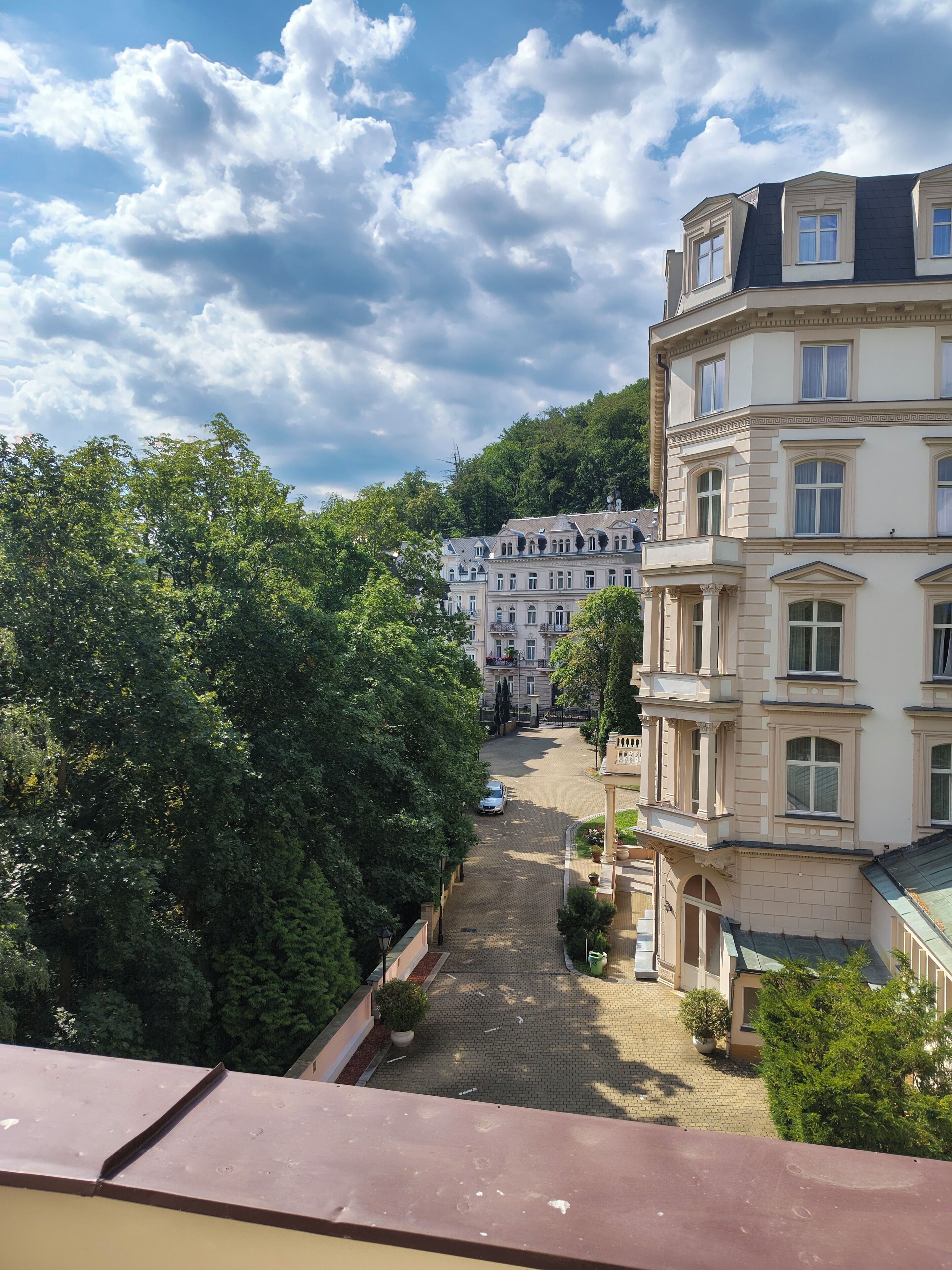 Un immeuble à plusieurs étages, doté d’une architecture classique, d’une cour pavée et entouré de verdure.