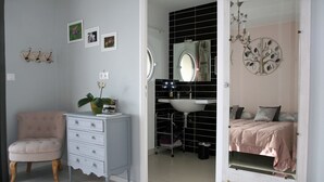 Une chambre à coucher avec un lit, une commode, un miroir et un mur décoré de tableaux.
