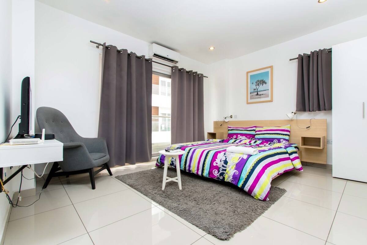 A modern bedroom with a bed, a desk, and a chair.