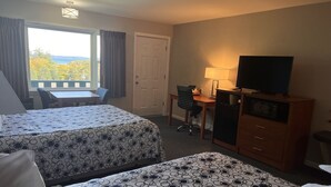 A hotel room with two beds, a desk, a chair, a television, and a view of the outdoors. - Edenbrook Motel (Bar Harbor)