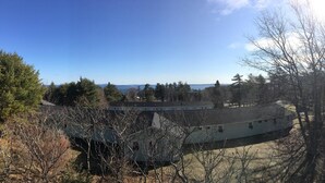 A building with a curved roof, surrounded by trees and a clear view of the water in the background. - Edenbrook Motel (Bar Harbor)